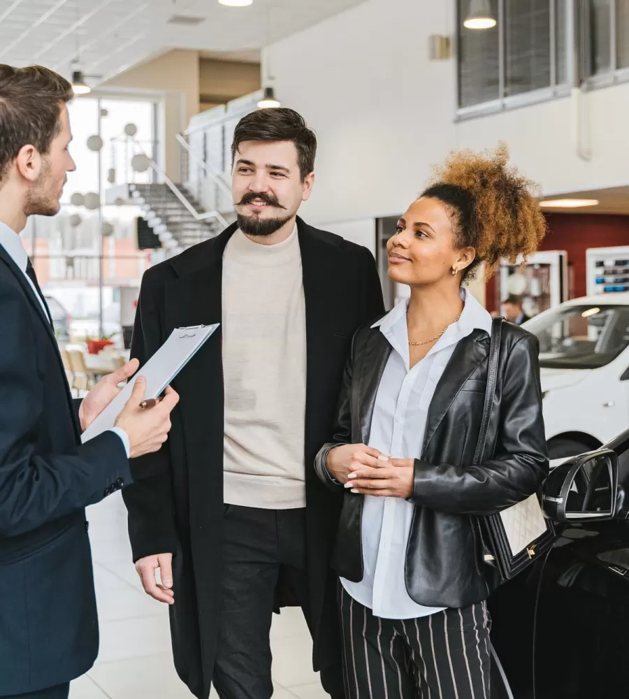 A salesperson walking a couple through a new vehicle on the showroom floor